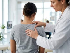 Chiropractor examining a patient's back and spine during an initial consultation at a chiropractic clinic in Pickering, Ontario.