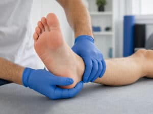 Licensed physiotherapist wearing blue gloves performing a manual foot and ankle assessment at a physiotherapy clinic in Pickering and Ajax.